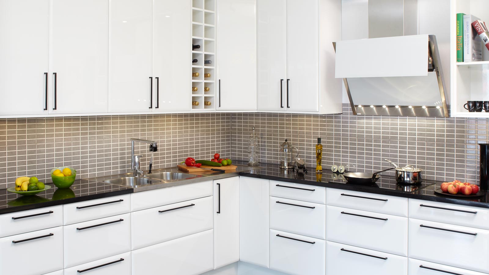 Nya köksluckor hittar du på Smartkök till ett bra pris. På bilden visas ett kök som går i vitt med svarta stilrena handtag och kakel med små rektangulära rutor i grått.